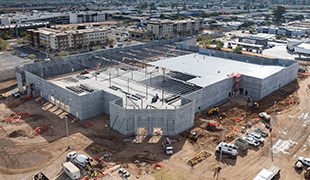 Aerial view of a retail store under construction showing structural walls, roof installation, and active site development.